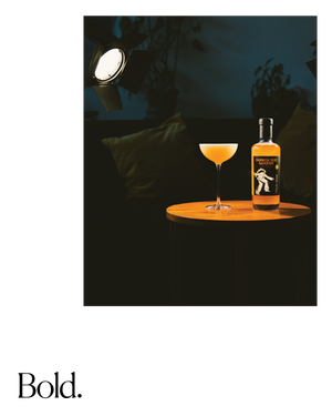 Bottle of passion fruit cocktail and glass under a spotlight