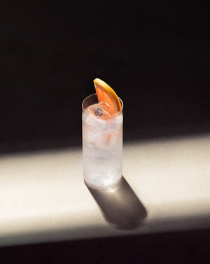 Paloma Cocktail in a clear highball glass with cubed ice garnished with a pink grapefruit slice.