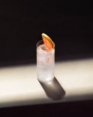 Paloma Cocktail in a clear highball glass with cubed ice garnished with a pink grapefruit slice.